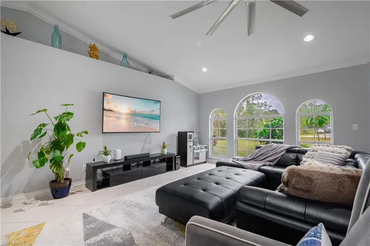 Living room with ornamental molding, ceiling fan, lofted ceiling, and tile patterned flooring