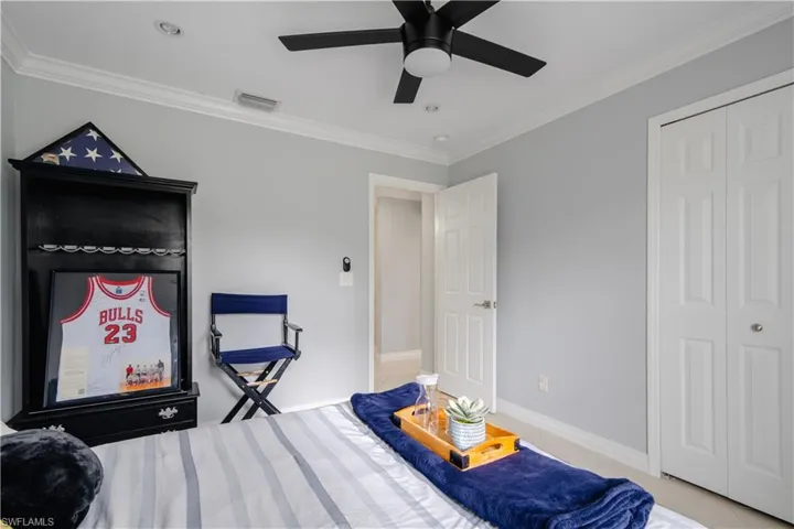 Bedroom with a closet, ceiling fan, crown molding, and light tile patterned flooring