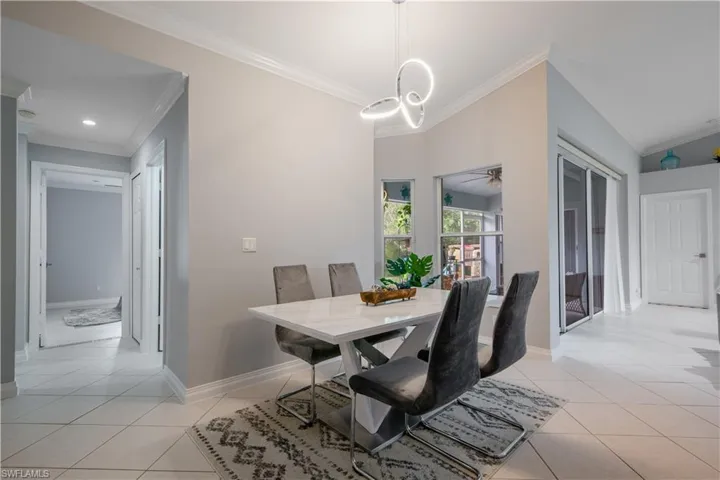 Tiled dining space featuring ornamental molding, lofted ceiling, and ceiling fan