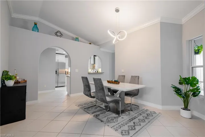Tiled dining room with crown molding and lofted ceiling