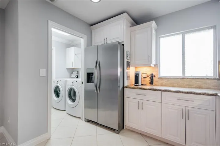 Laundry room with ornamental molding, washer and clothes dryer, and light tile patterned floors