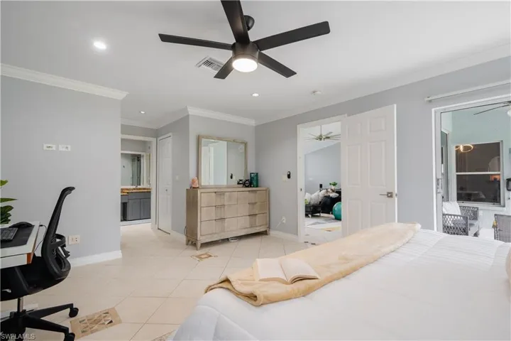 Bedroom with crown molding, ensuite bath, light tile patterned flooring, and ceiling fan