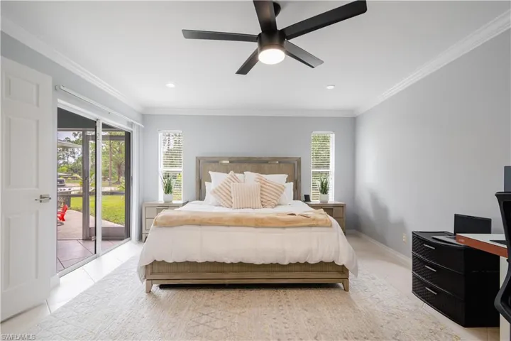Tiled bedroom with access to outside, ornamental molding, and ceiling fan