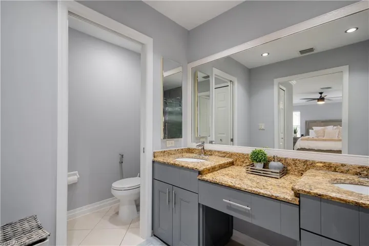 Bathroom featuring vanity, ceiling fan, toilet, and tile patterned flooring