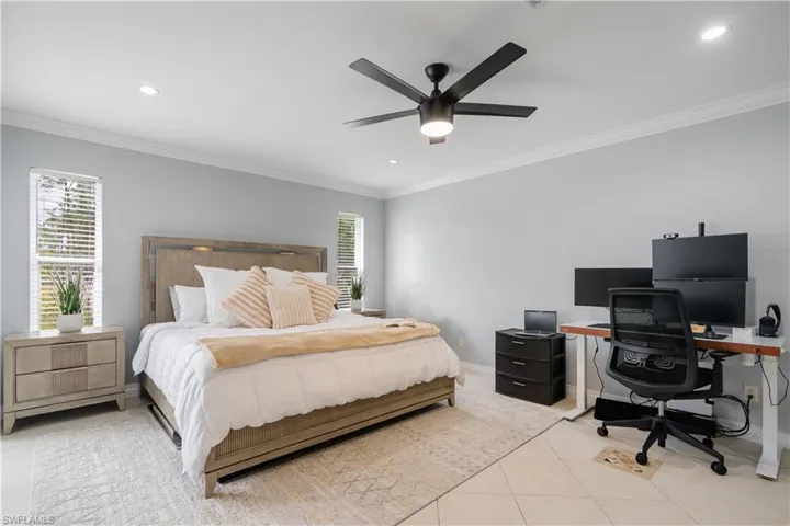 Tiled bedroom with ornamental molding and ceiling fan
