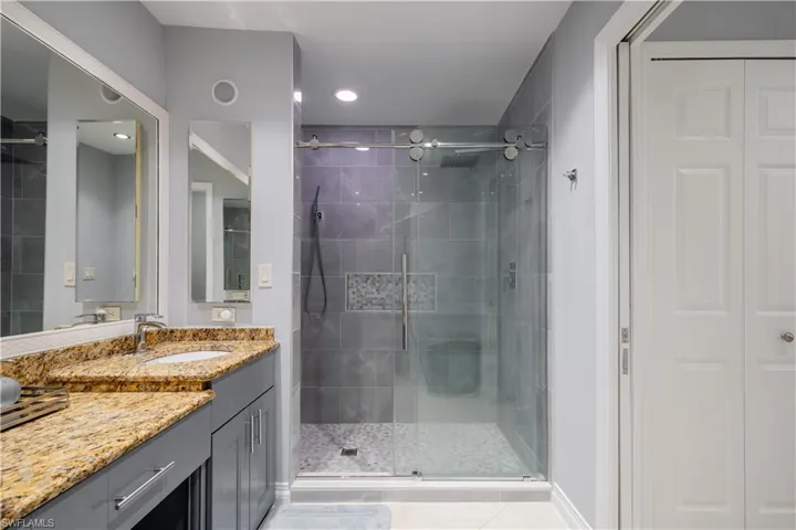 Bathroom with vanity, a shower with shower door, and tile patterned flooring