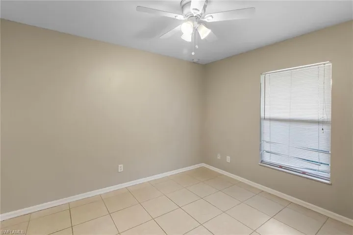 Empty room with a ceiling fan and light tile patterned floors