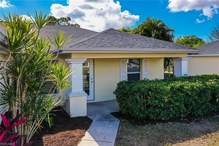 Property entrance with a shingled roof and stucco siding