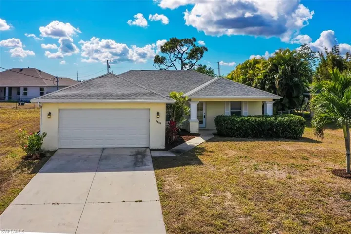 Ranch-style home with stucco siding, roof with shingles, driveway, and a front yard