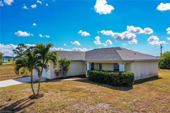 View of front of property featuring a shingled roof, a front yard, and concrete driveway