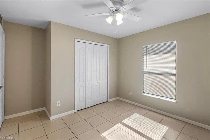 Unfurnished bedroom featuring a closet, light tile patterned flooring, and a ceiling fan