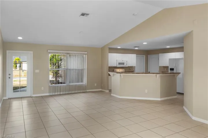 Unfurnished living room with recessed lighting, lofted ceiling, and light tile patterned floors