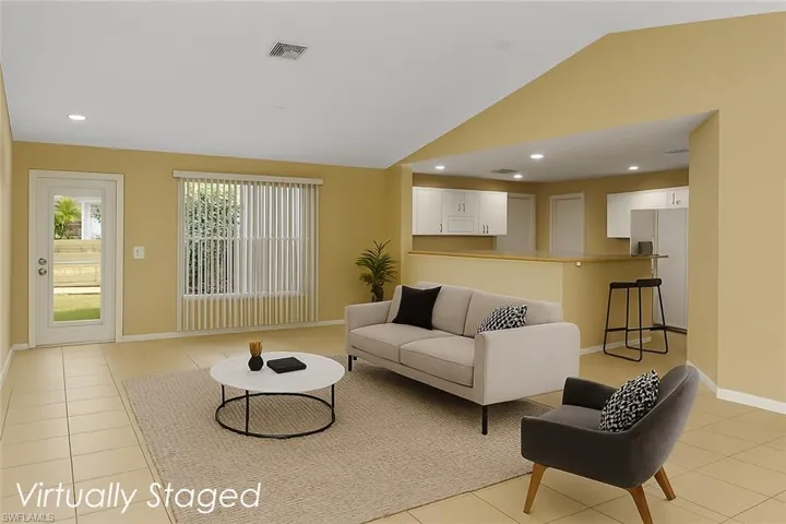 Living area featuring light tile patterned floors, recessed lighting, and vaulted ceiling