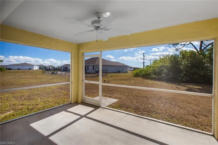 Unfurnished sunroom featuring ceiling fan and a residential view