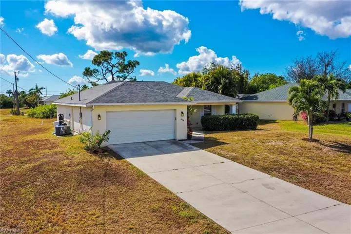 Ranch-style house featuring a front yard, stucco siding, concrete driveway, and a shingled roof