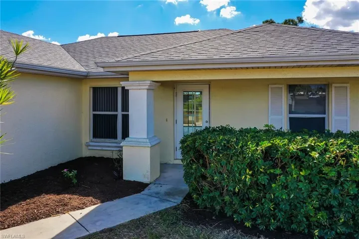 Property entrance featuring stucco siding and roof with shingles