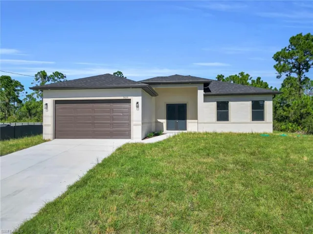 Prairie-style house with stucco siding, driveway, a front lawn, a garage, and roof with shingles