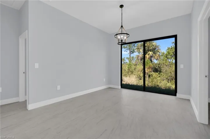 Empty room with baseboards and a chandelier