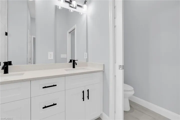 Bathroom with double vanity and light wood-type flooring