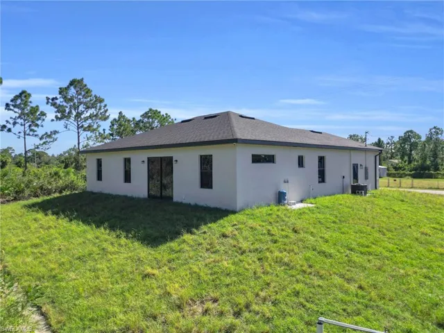 Back of house featuring stucco siding and a yard