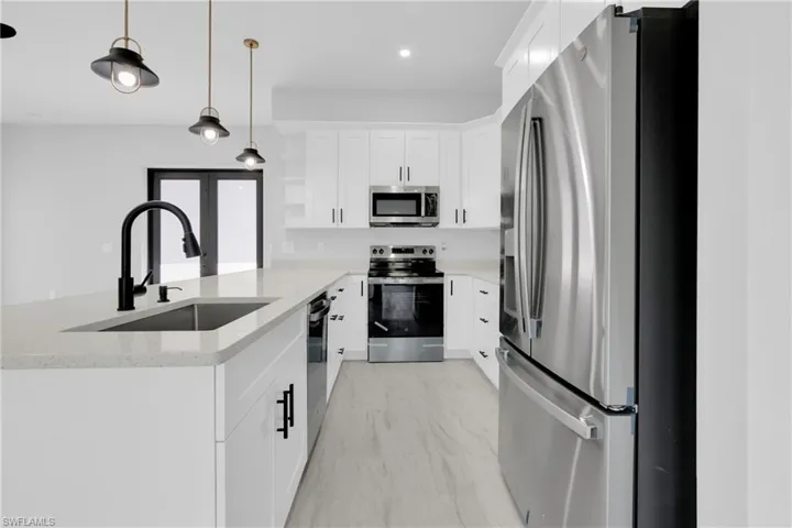 Kitchen featuring open shelves, stainless steel appliances, pendant lighting, a peninsula, and white cabinetry