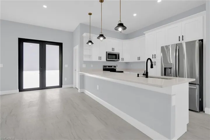 Kitchen with appliances with stainless steel finishes, white cabinetry, pendant lighting, a peninsula, and recessed lighting