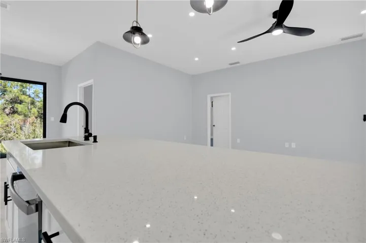 Kitchen with light stone countertops, recessed lighting, decorative light fixtures, and a ceiling fan