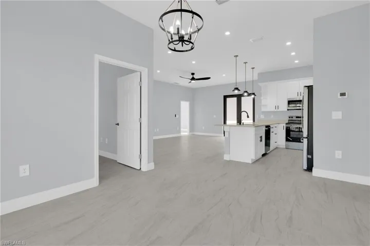 Kitchen featuring open floor plan, white cabinets, a ceiling fan, decorative light fixtures, and a chandelier
