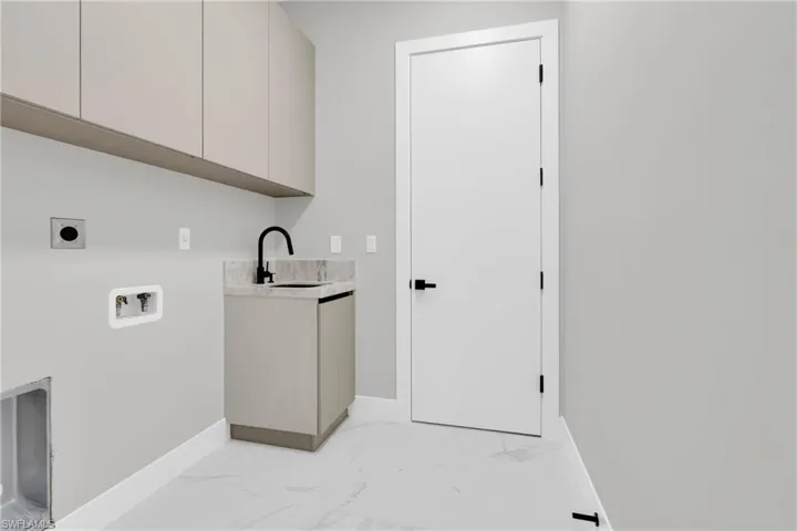 Laundry room featuring hookup for an electric dryer, light marble finish floors, washer hookup, and cabinet space