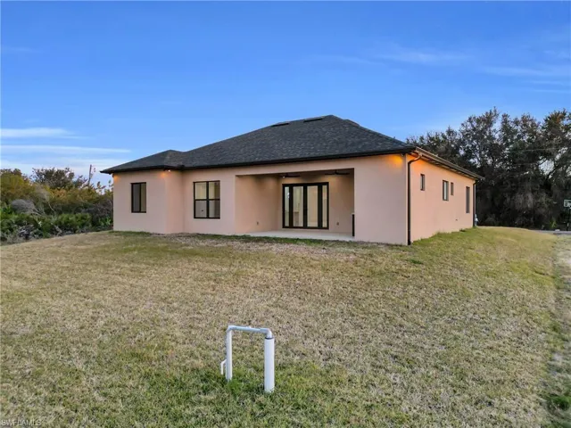 Rear view of property with a yard, stucco siding, a patio, and a ceiling fan