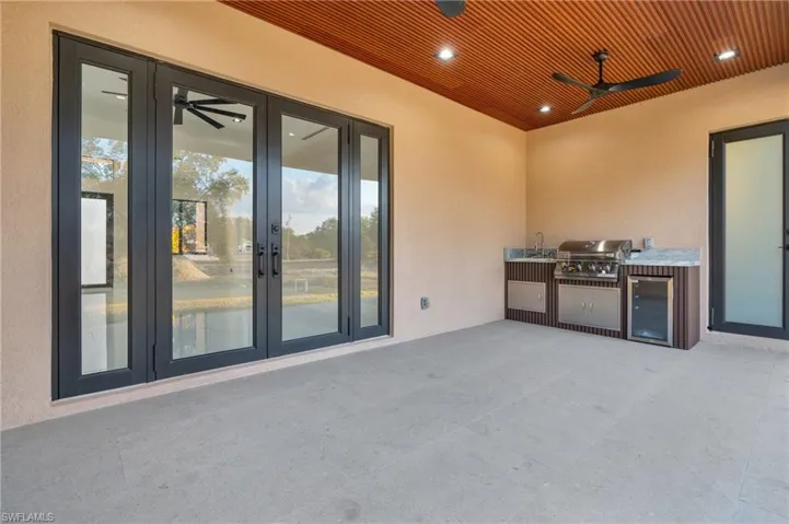 View of patio with area for grilling, french doors, beverage cooler, and ceiling fan