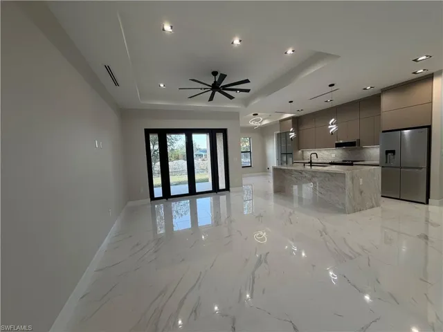 Kitchen with open floor plan, gray cabinetry, modern cabinets, stainless steel appliances, and a center island with sink
