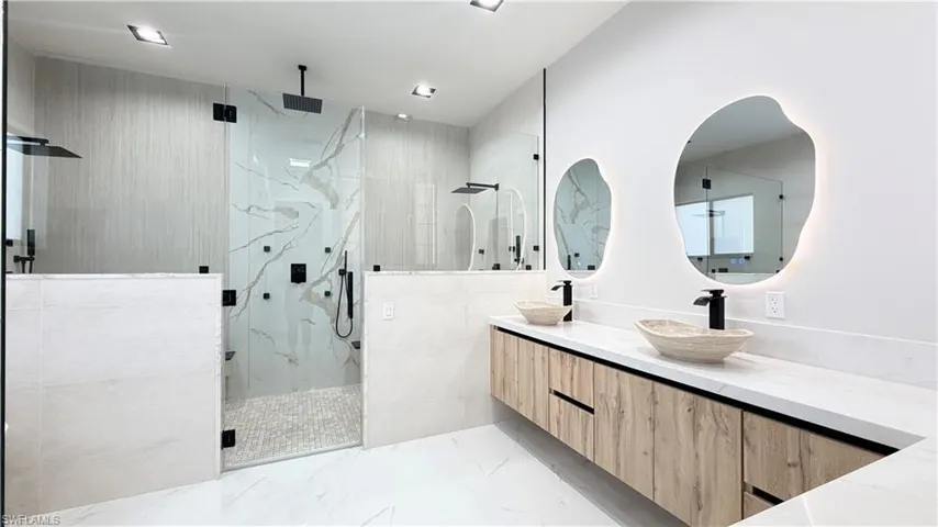 Bathroom featuring a marble finish shower and double vanity