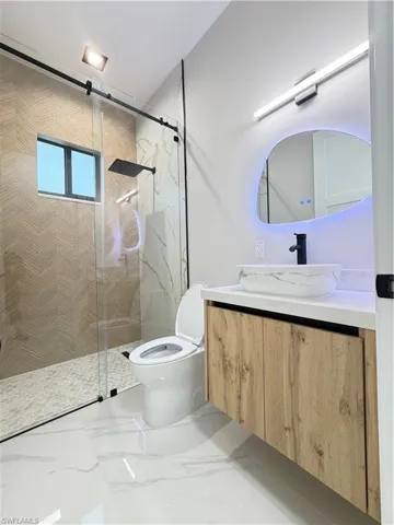 Full bath with vanity, a marble finish shower, and light marble finish floors