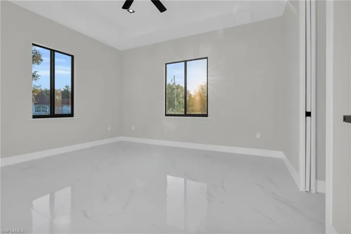 Spare room with light marble finish floors and ceiling fan