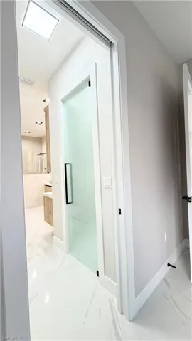 Hall featuring baseboards and light marble finish floors