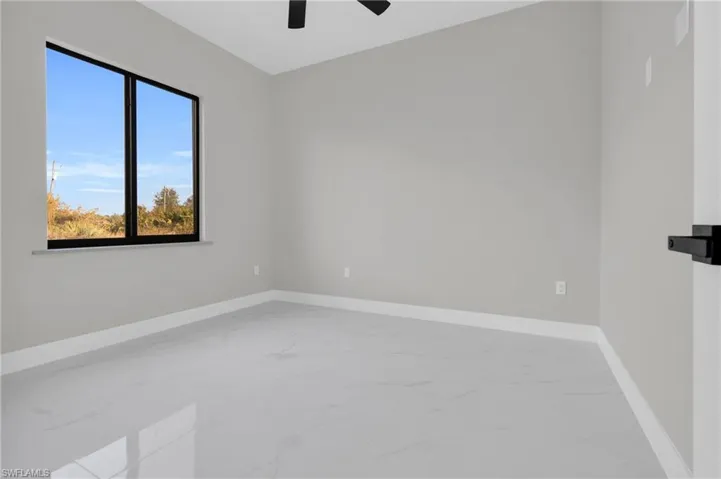 Unfurnished room with light marble finish floors and a ceiling fan