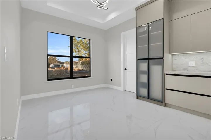 Unfurnished bedroom featuring light marble finish flooring and a tray ceiling