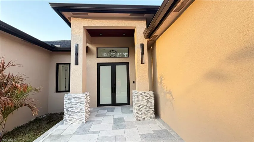View of exterior entry featuring french doors, stucco siding, and a patio