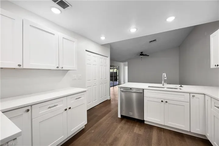 Kitchen with white cabinetry, dark wood-style flooring, dishwasher, ceiling fan, and a peninsula