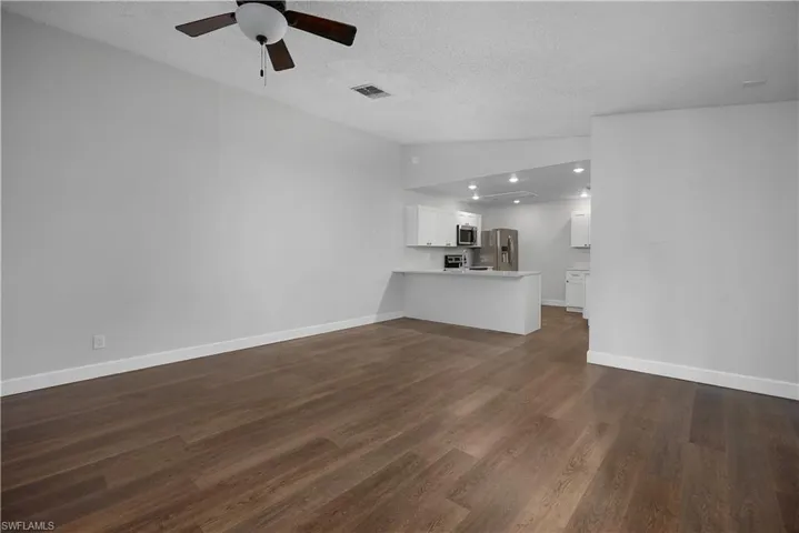 Unfurnished living room with lofted ceiling, dark wood-style floors, ceiling fan, and a textured ceiling