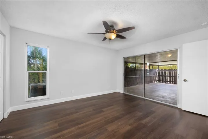 Unfurnished room featuring healthy amount of natural light, dark wood-style floors, a ceiling fan, and a textured ceiling