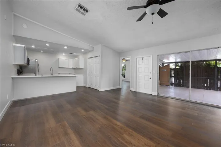 Unfurnished living room with vaulted ceiling, a ceiling fan, a textured ceiling, dark wood finished floors, and recessed lighting