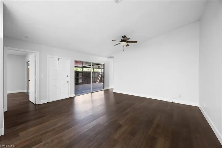 Empty room featuring lofted ceiling, dark wood-style flooring, and ceiling fan
