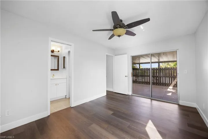 Unfurnished bedroom featuring dark wood finished floors, access to exterior, and a ceiling fan