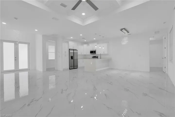 Unfurnished living room featuring coffered ceiling, beamed ceiling, recessed lighting, light marble finish floors, and ceiling fan