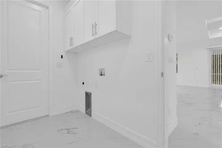 Laundry area featuring light marble finish floors, washer hookup, electric dryer hookup, and cabinet space