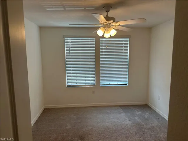 Carpeted spare room featuring ceiling fan and a wealth of natural light