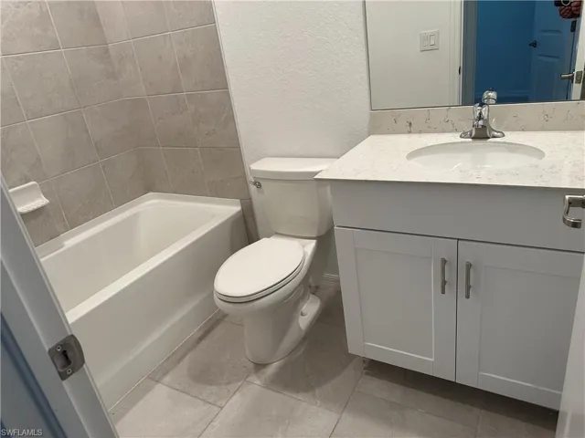 Full bathroom featuring tile floors, washtub / shower combination, toilet, and vanity with extensive cabinet space