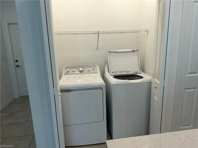 Clothes washing area featuring washer and dryer and dark tile flooring